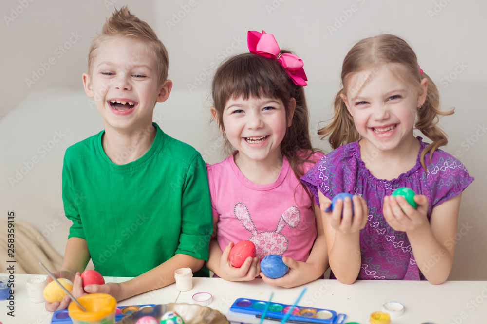 cute twin triplets children, first graders, painted easter eggs and looking at the camera, smiling cute twin triplets children, first graders, painted easter eggs and looking at the camera, smiling