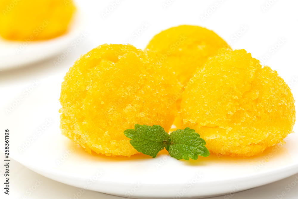 Mango sorbet, summer dessert decorated with mint leaves. Closeup of a bowl of mango sorbet. Mango sorbet, summer dessert decorated with mint leaves. Closeup of a bowl of mango sorbet.