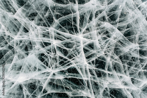 Fototapeta Naklejka Na Ścianę i Meble -  Texture of frozen ice with cracks, frozen like a cobweb. Baikal, Russia