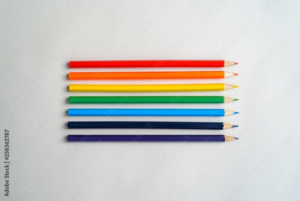 Flat lay of pencils set in rainbow colors on blank sheet of white paper, pointing sideways Flat lay of pencils set in rainbow colors on blank sheet of white paper, pointing sideways