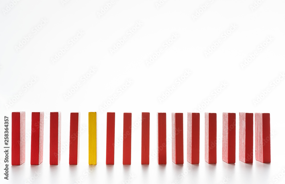 Yellow wooden block between row of red ones on white Yellow wooden block between row of red ones on white