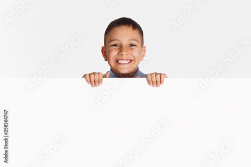 Advertising. Little kid standing behind blank banner