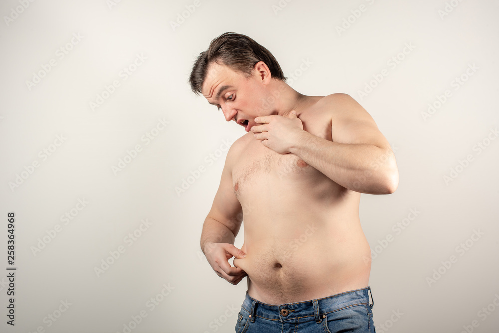 A man in jeans with a fat belly and a naked torso on a white background.
