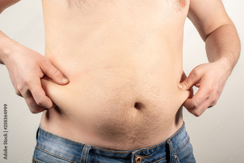 Naklejka premium A man in jeans with a fat belly and a naked torso on a white background.