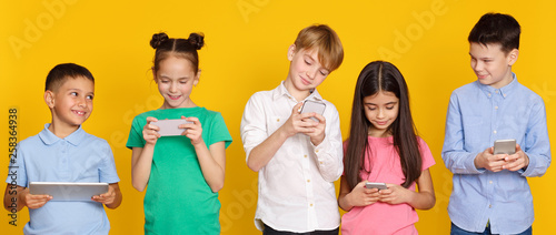 Gadget addiction. Children with modern gadgets, yellow background