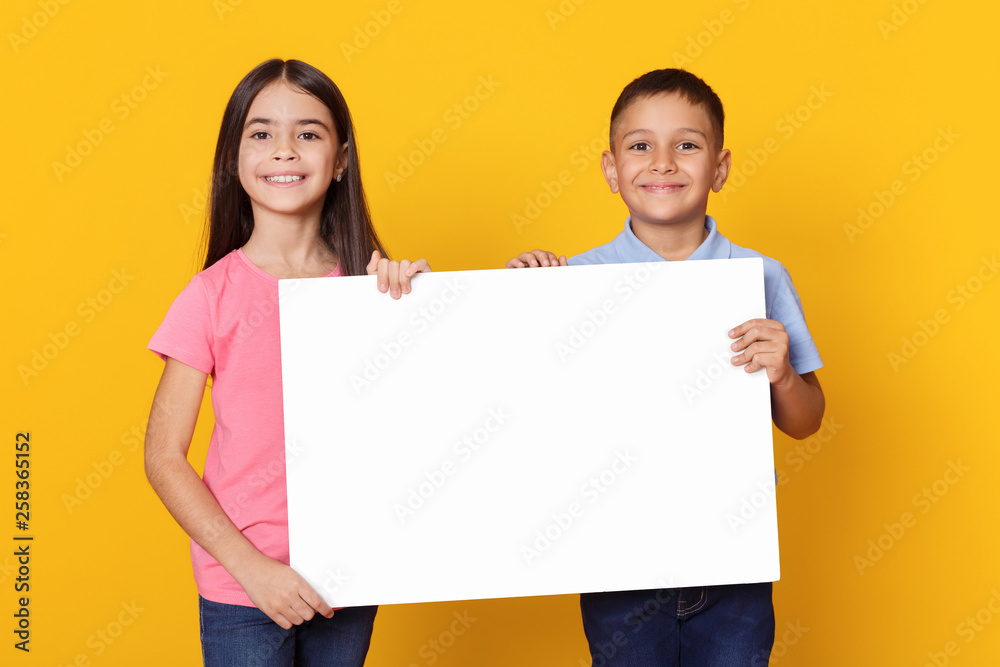 Boy and girl holding empty board for advertisement Boy and girl holding empty board for advertisement