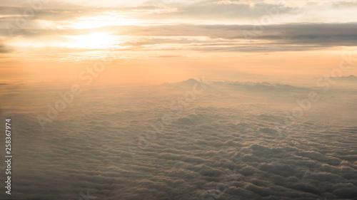 Aerial traveling. Flying at dusk or dawn. Fly through orange cloud and sun.