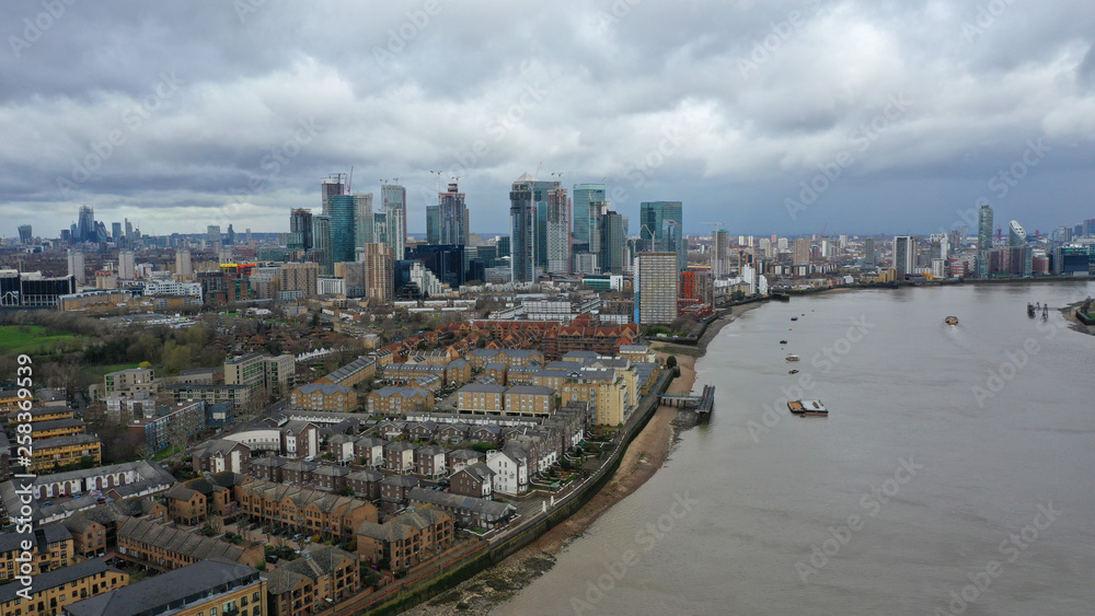 Fototapeta premium Aerial bird's eye view photo taken by drone of Canary Wharf skyline as seen from river Thames with beautiful cloudy sky, Isle of Dogs, London, United Kingdom