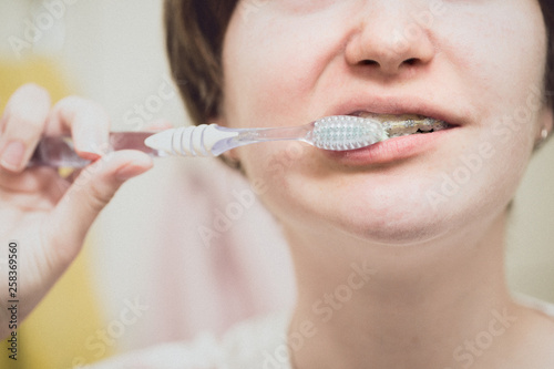 girl with braces brushing her teeth