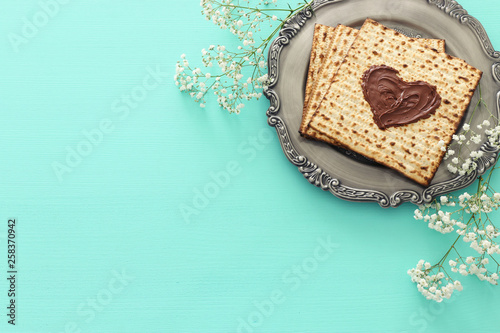 Pesah celebration concept (jewish Passover holiday) with chocolate heart over matzah. Top view flat lay