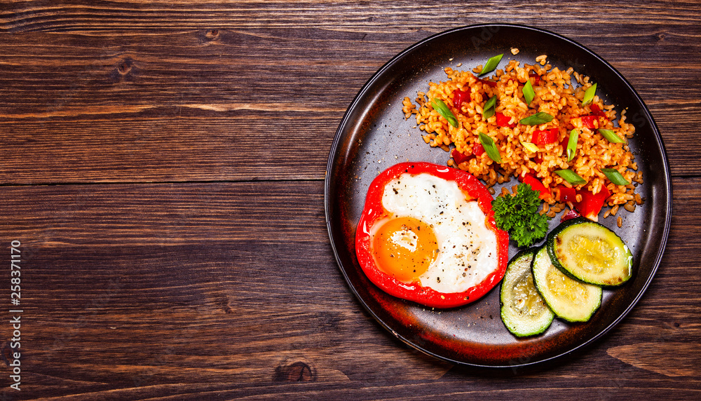 Fried egg, groats and vegetables on wooden table Fried egg, groats and vegetables on wooden table