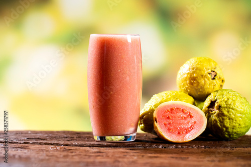Konstfotografi fruits and red guava juice in a glass on a wooden table, outdoor.