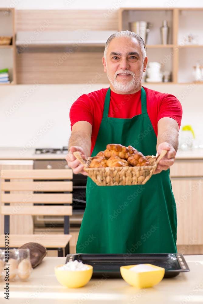 Old male baker working in the kitchen