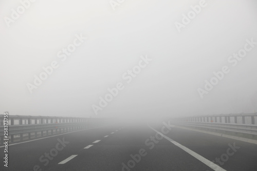 highway with very dense dangerous fog without cars in winter