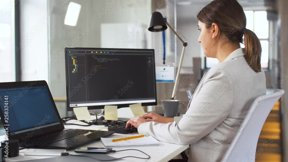 business, programming and technology concept - female programmer with script on computer screen working at office business, programming and technology concept - female programmer with script on computer screen working at office