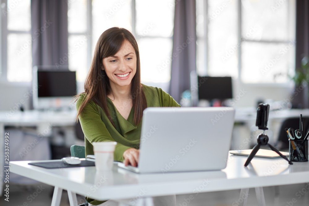 Beautiful smiling Caucasian businesswoman sitting in modern office and using laptop. Beautiful smiling Caucasian businesswoman sitting in modern office and using laptop.