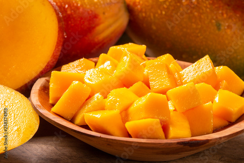 Mango fruit and mango cubes on the wooden table.