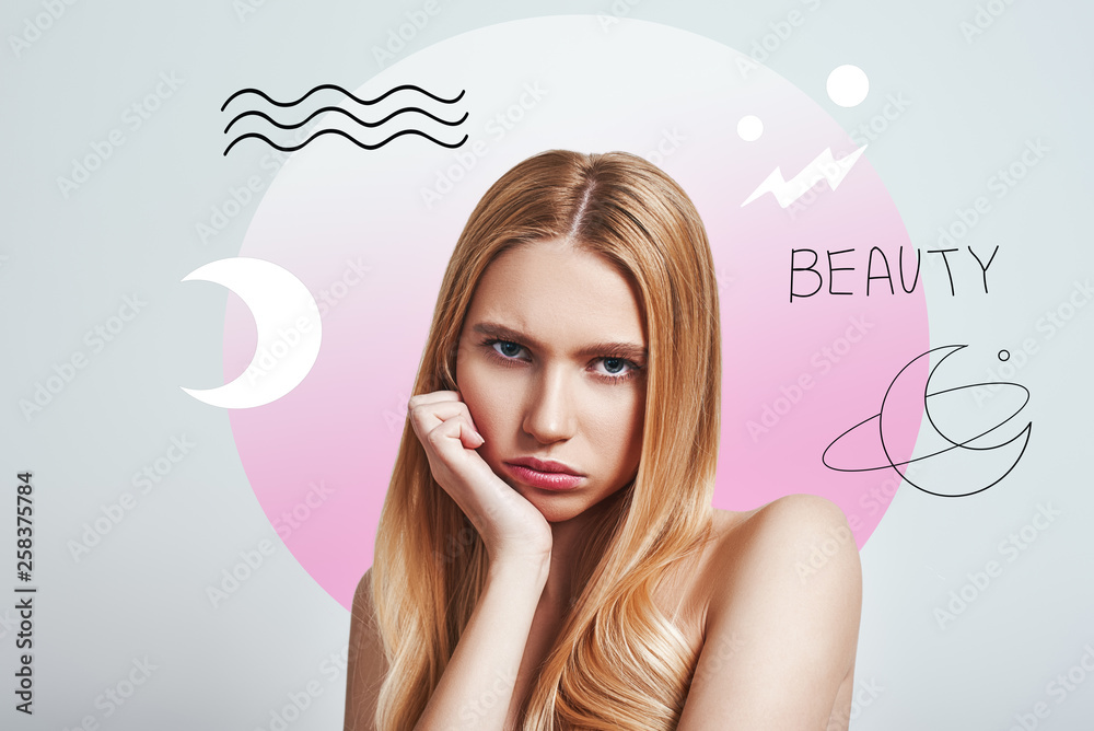 Tired of attention. Upset young blonde woman looking at camera and making a sad face while standing against abstract pink circle and hand drawn illustrations. Tired of attention. Upset young blonde woman looking at camera and making a sad face while standing against abstract pink circle and hand drawn illustrations.