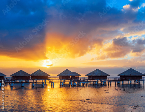Water Bungalows with a idyllic Sunset, beautiful Sky and Clouds in the Lagoon Huahine, French Polynesia. Copy space for text.