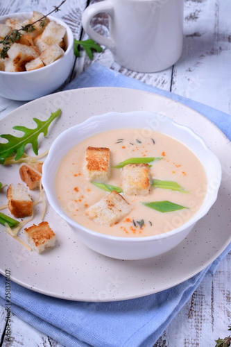 Cream soup with croutons, green onion and cheese in a white bowl