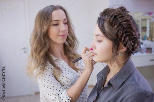 Stylist makeup artist doing makeup and hair in a beauty salon. Professional make-up