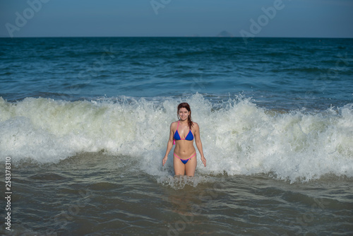 beautiful young woman in a seductive bikini comes out of the sea with high waves. Big waves in the ocean © Михаил Решетников