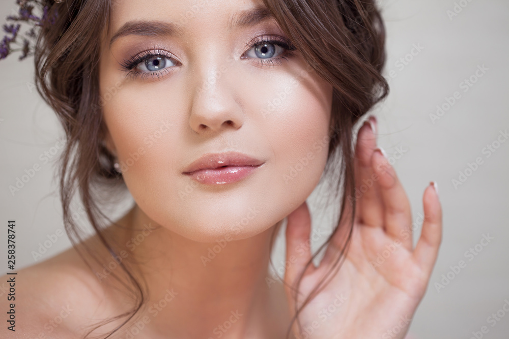 Fototapeta premium Young brunette woman with beautiful spring look, hairstyle with weave and blue flowers