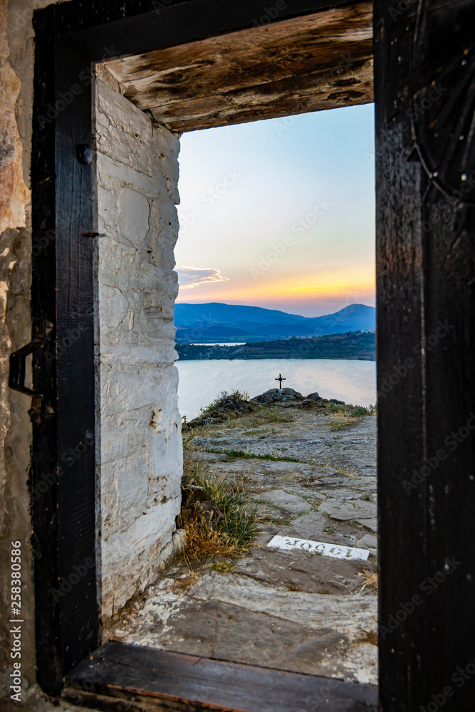 Exterior view through the door of the medieval non-functioning Church of St. John Letni at Pchelina Reservoir, Western Bulgaria on an August evening Exterior view through the door of the medieval non-functioning Church of St. John Letni at Pchelina Reservoir, Western Bulgaria on an August evening