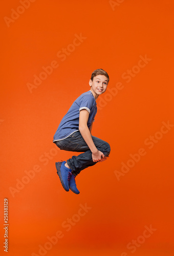 Emotional boy jumping in bomb style on orange