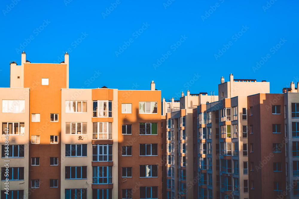Modern houses of a new building. A contrast shadow on the building. Sunny day, blue sky. Yard. Yellow walls.
