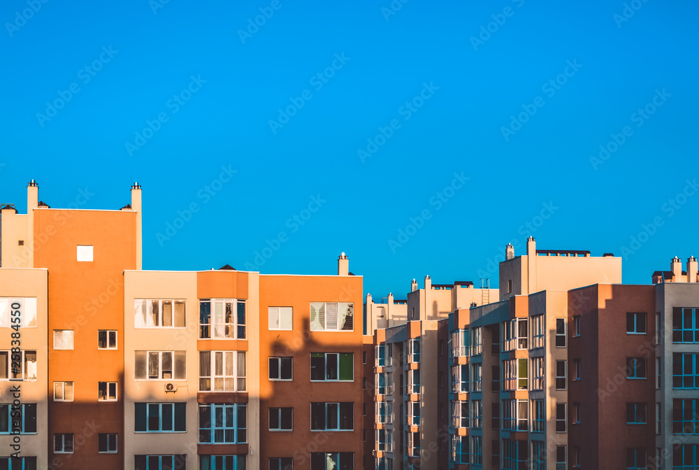 Modern houses of a new building. A contrast shadow on the building. Sunny day, blue sky. Yard. Yellow walls.