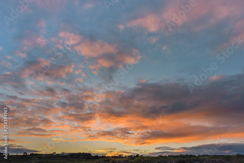 Landscape with colorful clouds in orange and pink against blue sky