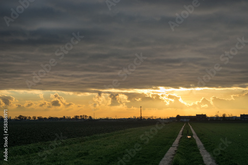 A low winter sun is shining below a layer of clouds causing a dramatic sky © Menyhert