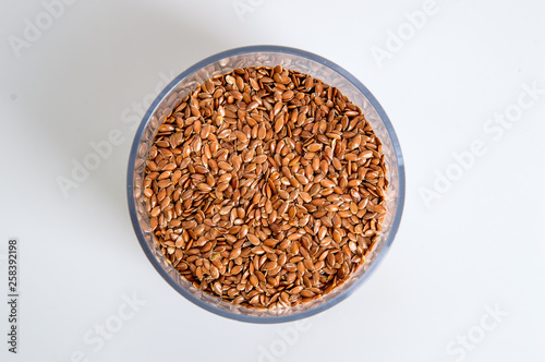 Top view. A jar filled with brown flax seeds. White background. Close up, macro.