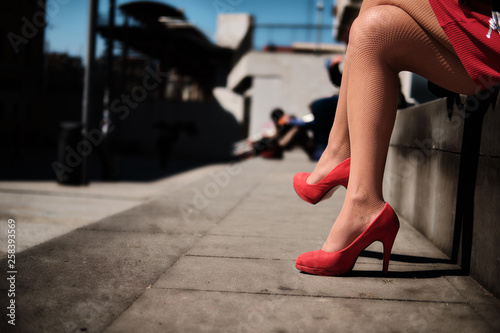 Legs of young girl with red high-heeled shoes