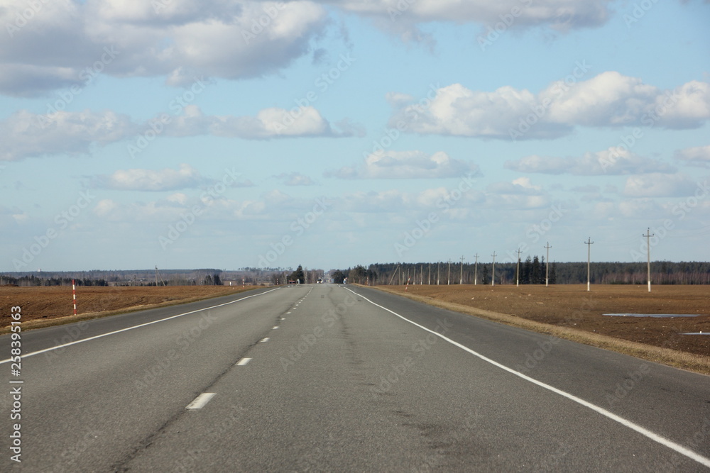 Suburban asphalt road in perspective vith forest line on horizon - spring landscape Suburban asphalt road in perspective vith forest line on horizon - spring landscape