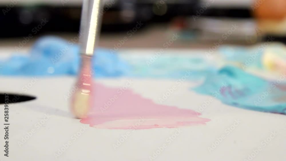 Artist mixes different colors of acrylic paint with a brush for drawing. Preparation of colors for drawing pictures Artist mixes different colors of acrylic paint with a brush for drawing. Preparation of colors for drawing pictures