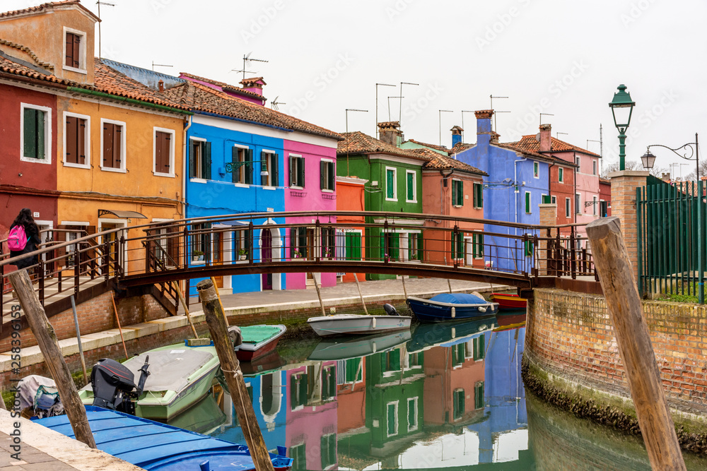 Italy, Venice, Burano, canals and boats among the typical colored houses.
