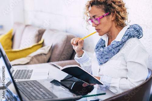 Adult woman at home working with modern technology laptop and old paper together at the same time - concept tf freelance in alternative office and businesswoman with online work photo