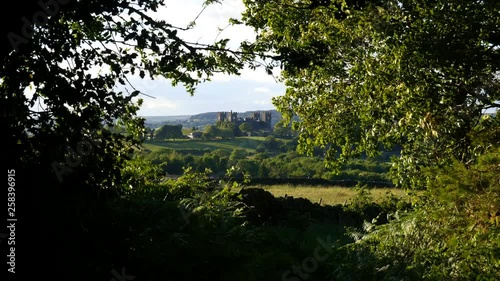 Typical English 18th century manor house in form of a medieval castle, seen from a forest with strong wind blowing the trees.