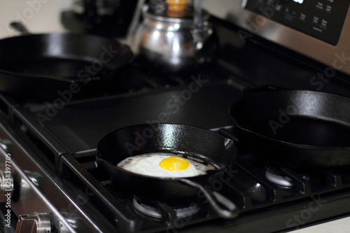 Egg sunny side up frying in a pan on the stove.
