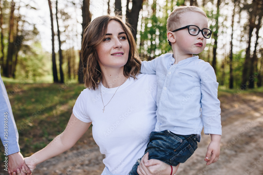 The family is going on a picnic in the forest. Mom, son. Summer walk. Picnic set. Dog. The kid with glasses. Beautiful family. The family is going on a picnic in the forest. Mom, son. Summer walk. Picnic set. Dog. The kid with glasses. Beautiful family.