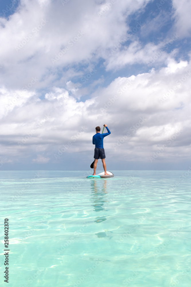 Young Adult Man with stand up paddle in clear blue water Young Adult Man with stand up paddle in clear blue water