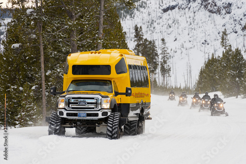 Tracked vehicle and snowmobiles on a snowy track