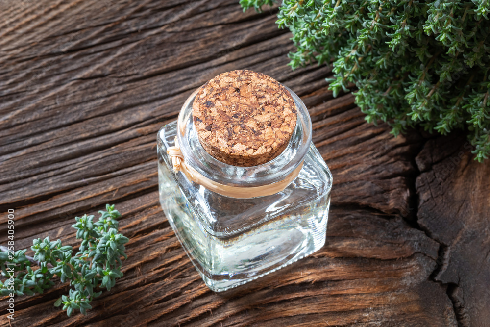 A bottle of thyme essential oil with fresh thyme