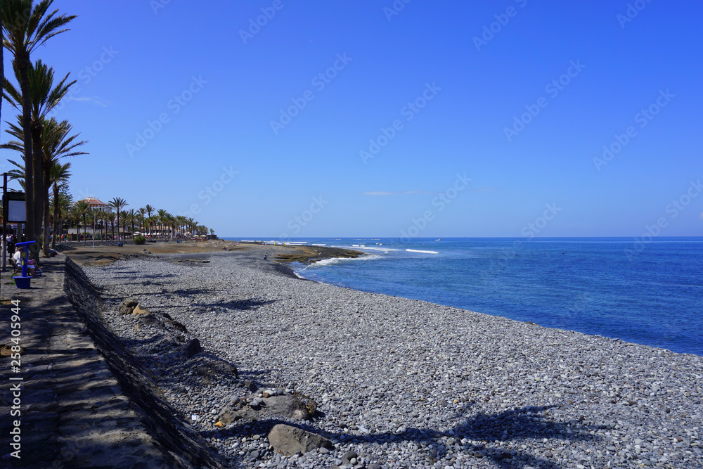Shoreline of Las Americas and palm trees shadows on a sunny day in Tenerife, Canary Islands, Spain 