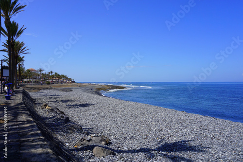 Shoreline of Las Americas and palm trees shadows on a sunny day in Tenerife  Canary Islands  Spain 