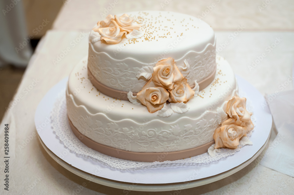 Fototapeta premium White wedding cake with flowers. Dessert for guests.