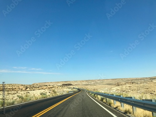 A photo showing an empty asphalt road in a desert climate, made sunny on a clear day.