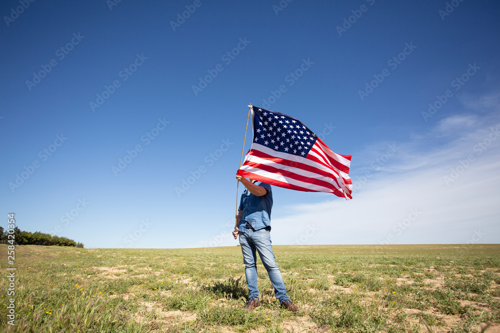 Man holding American flag on field in remote landscape